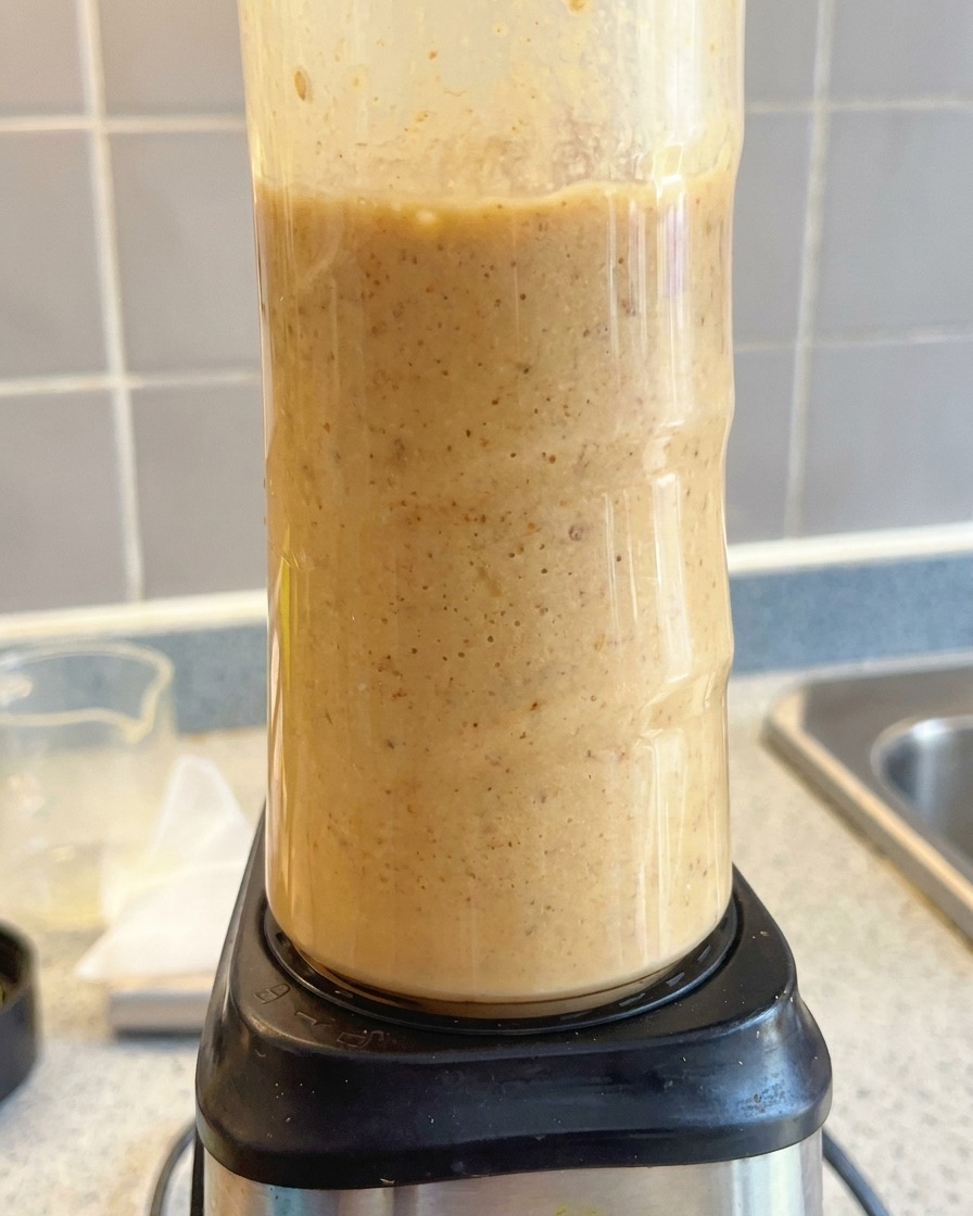 Ein Standmixer püriert die cremige, hellbraune Ramen-Basis glatt.