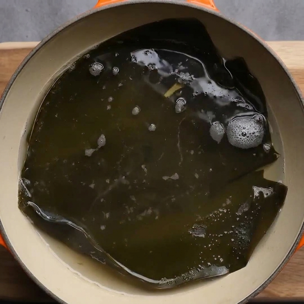 Ein großes Stück getrockneter Kelp simmert in kochendem Wasser.