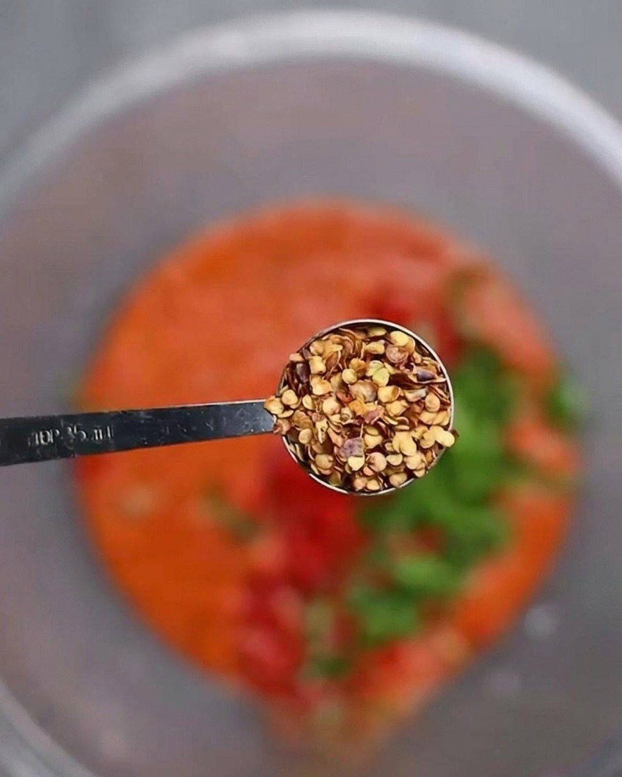 Chilisamen werden über die rote Chilipaste und das gehackte Gemüse gestreut.