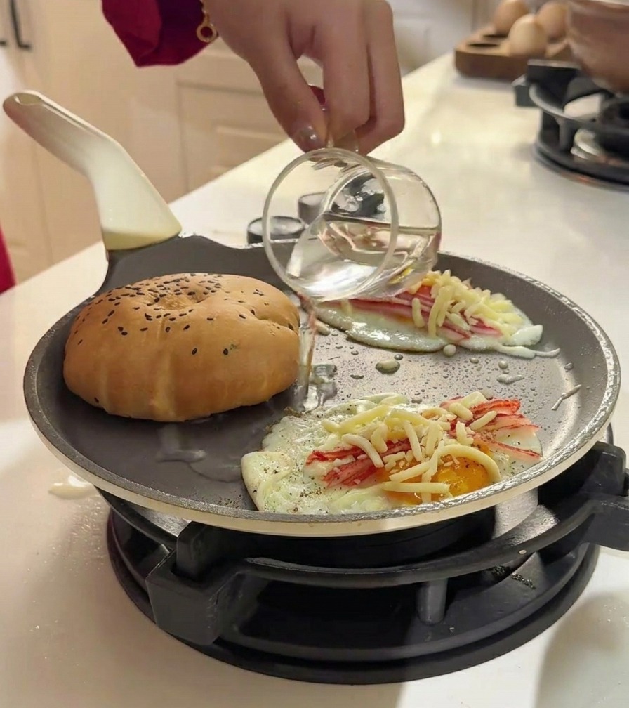 Wasser wird vorsichtig in die Pfanne neben das Brötchen gegossen, um Wasserdampf zu erzeugen.