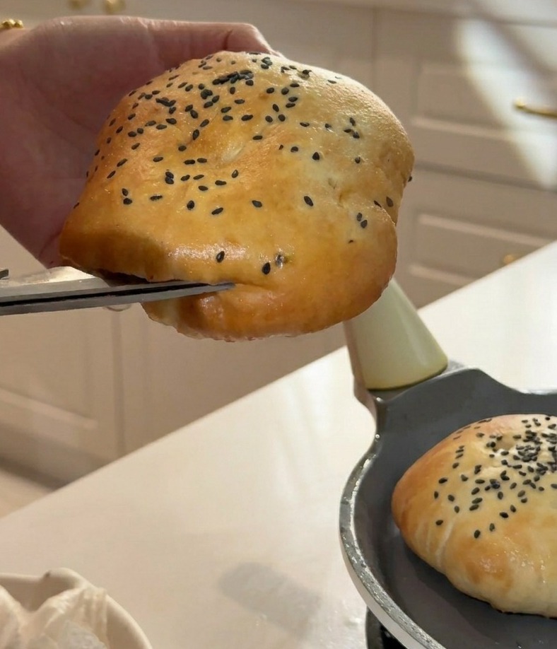 Mit einer Küchenschere wird die Seite des weichen Burgerbrötchens aufgeschnitten, um eine Tasche zu bilden.