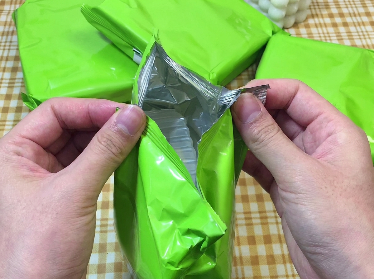 Zwei Hände reißen eine grüne Instant-Ramen-Packung auf und legen die Nudeln frei.