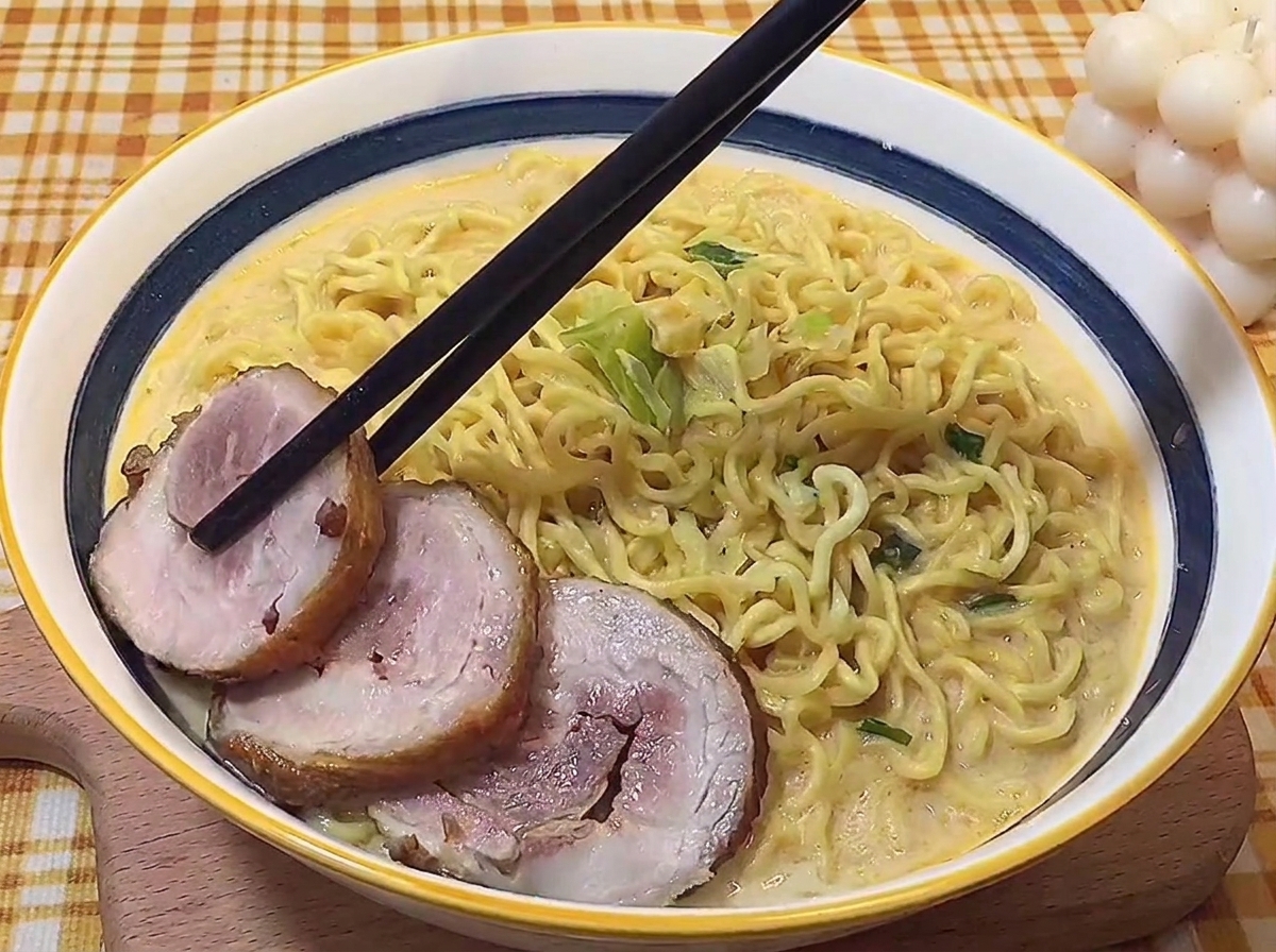 Essstäbchen legen Scheiben des geschmorten Schweinebauchs in eine Schüssel mit heißen Ramen.