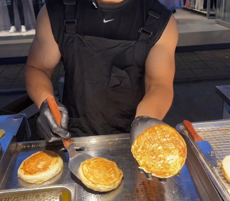 Eine Person hält eine Hälfte des Burgerbrötchens hoch, um die knusprige, goldbraune Innenseite zu zeigen.