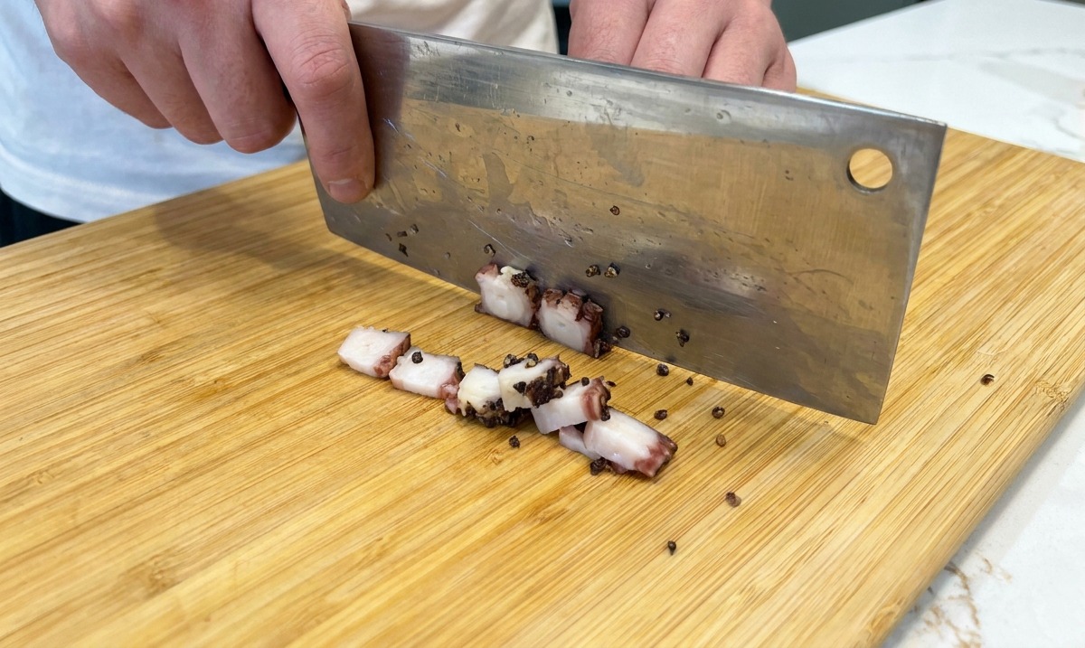 Schweinebacke wird mit einem Messer in kleine Würfel geschnitten.