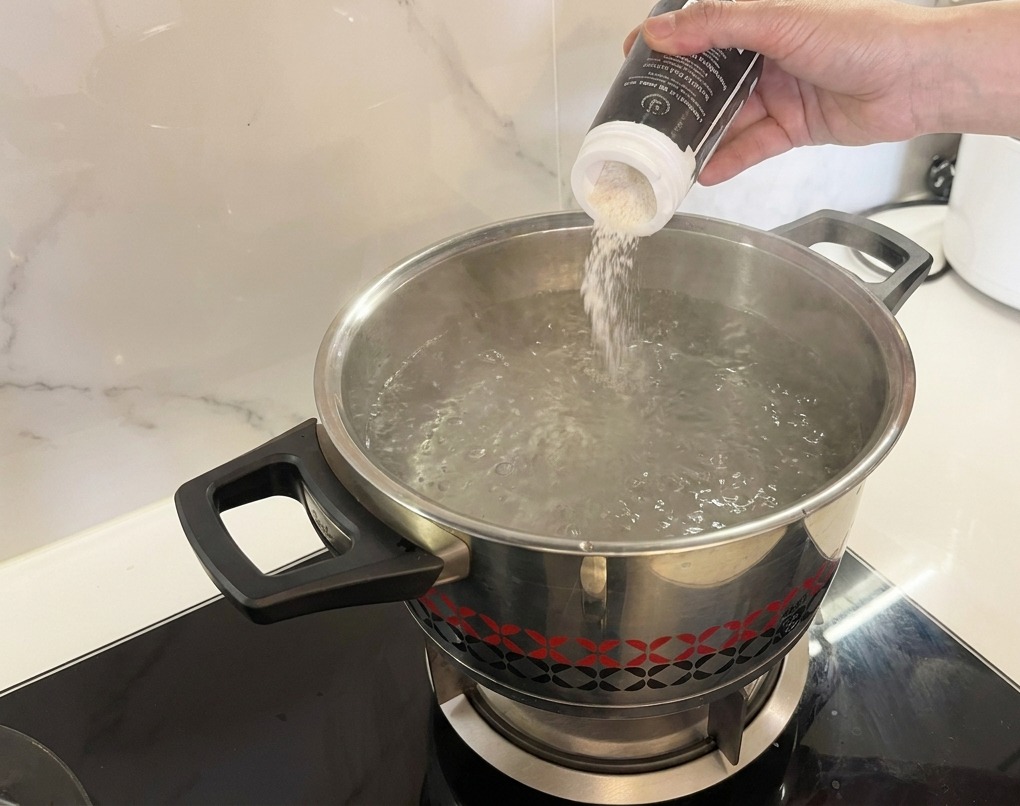 Salz wird in einen Topf mit sprudelnd kochendem Wasser geschüttet.