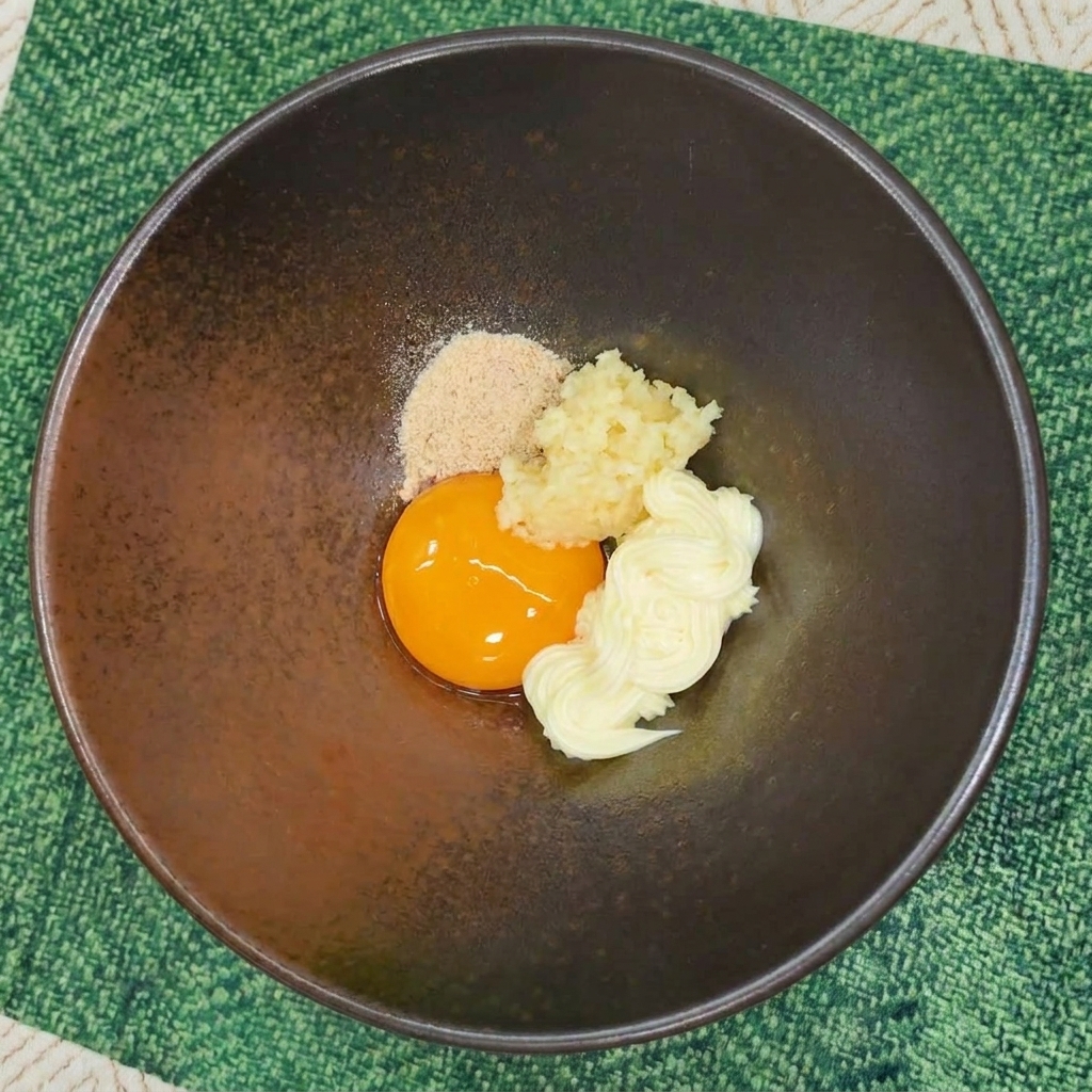 Instant-Nudel-Gewürzpulver wird in die Schüssel mit Eigelb, Knoblauch und Mayonnaise gegeben.