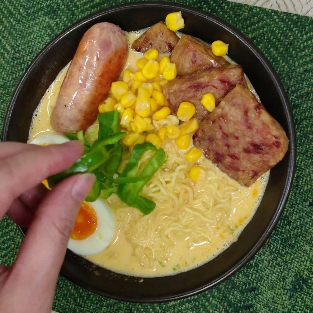 Eine Hand platziert frische Paprikastreifen auf der cremigen Suppe.