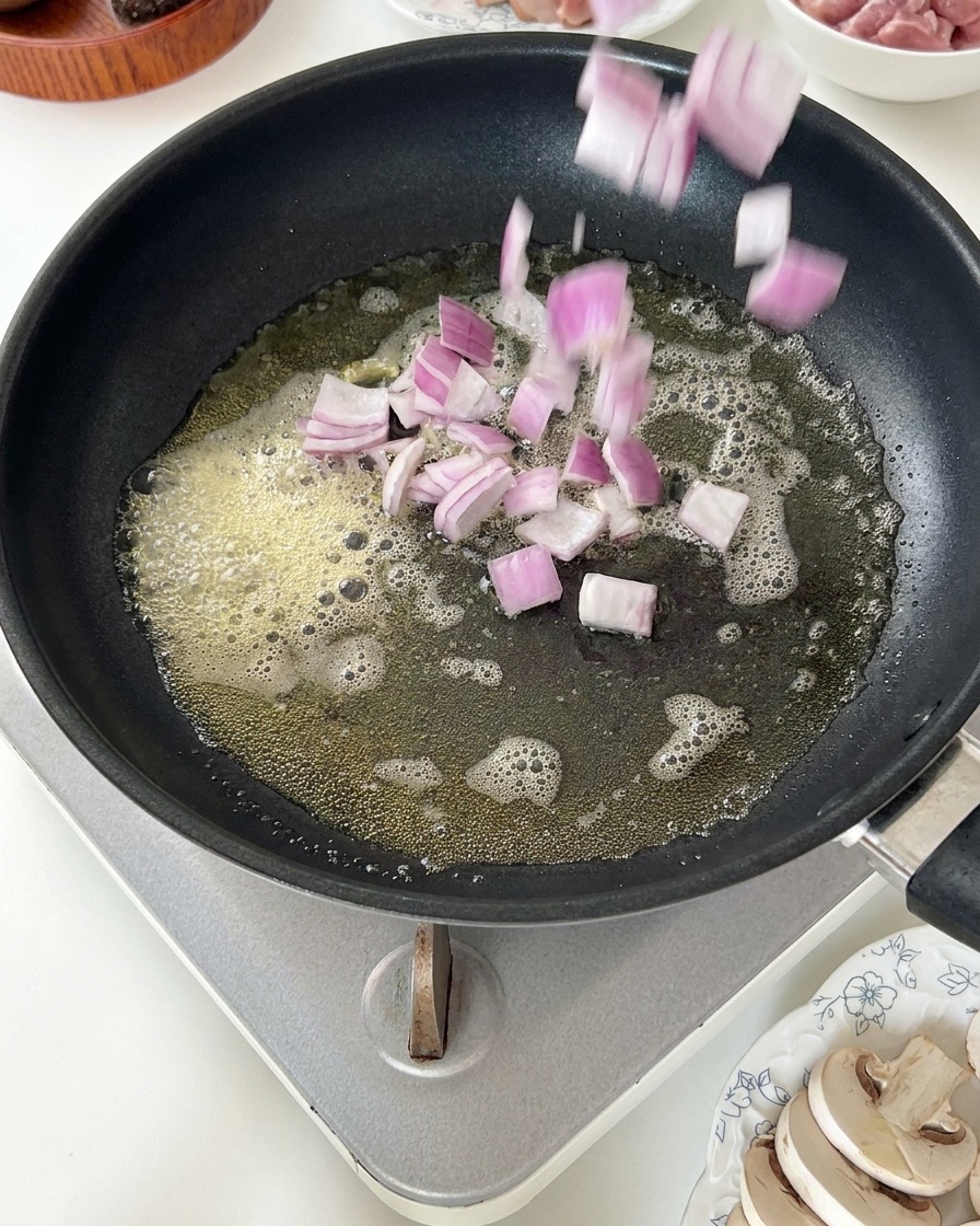 Rote Zwiebelwürfel werden in schäumende Butter gegeben.