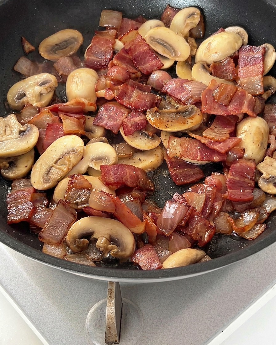 Pfanne mit Speck und Pilzen, bestreut mit schwarzem Pfeffer.