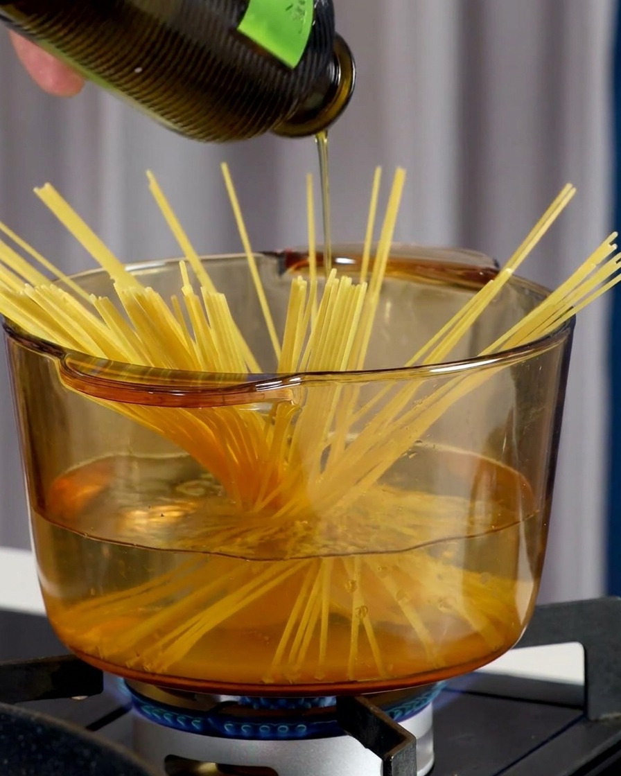Eine Hand streut Meersalz in kochendes Wasser mit Spaghetti.