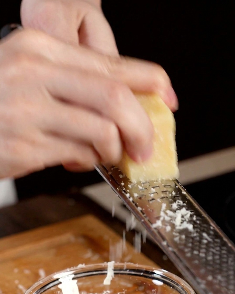 Parmesan wird direkt in eine Schüssel mit einem Eigelb gerieben.