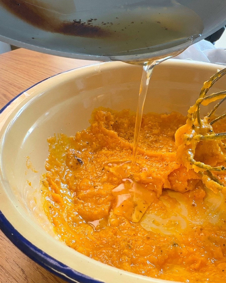 Goldenes, flüssiges Fett wird aus der Pfanne in die Schüssel mit der Eigelbmischung gegossen.