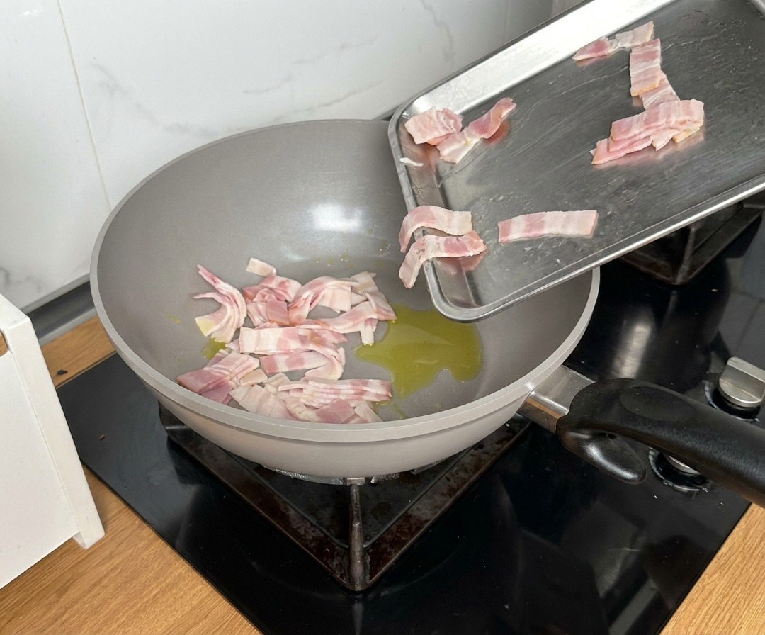 Speckstücke werden in eine Pfanne mit heißem Öl gegeben.