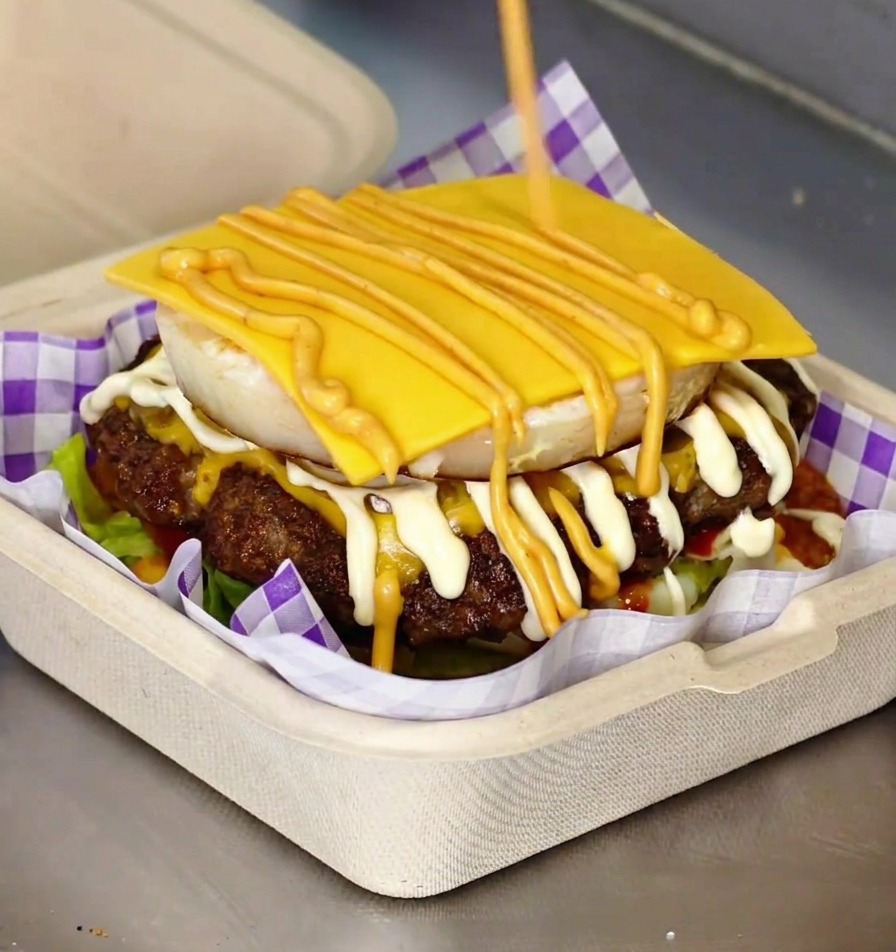 Ein fertiger Gourmet-Burger mit sichtbarem Spiegelei und geschmolzenem Käse im Brioche-Bun.