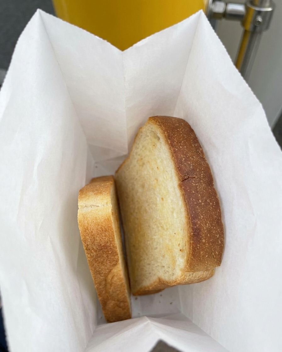 Zwei dicke Scheiben weißes Sandwichbrot liegen in einer mit Papier ausgelegten Plastiktüte.