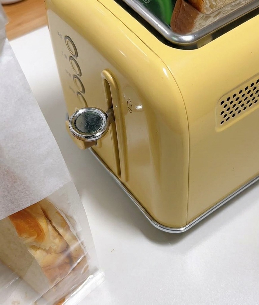 Dicke Weißbrotscheiben stecken in den Schlitzen eines gelben Toasters im Vintage-Stil.