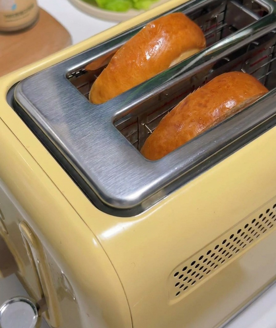 Zwei Scheiben gebräunter Toast springen aus einem gelben Vintage-Toaster.