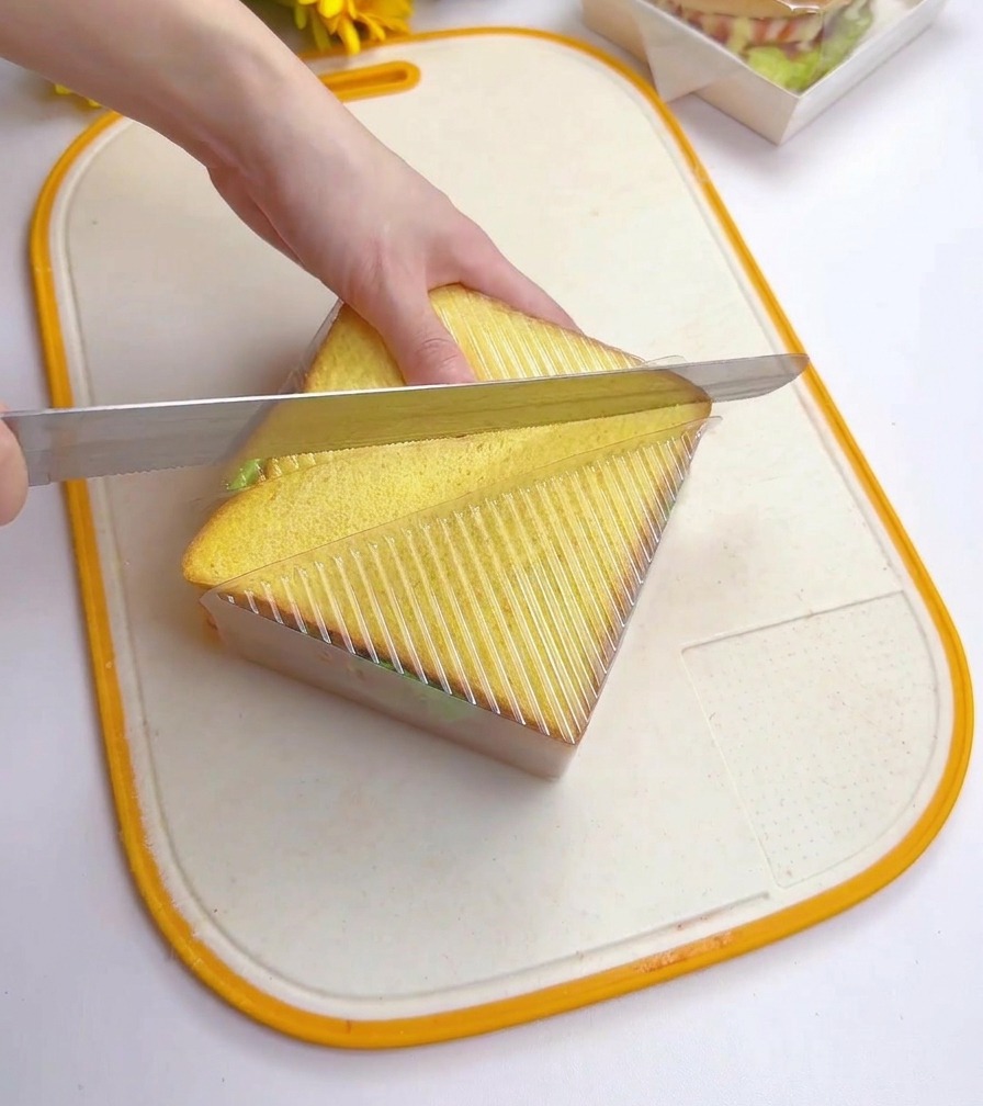 Ein Brotmesser schneidet das Sandwich in der Form diagonal durch.