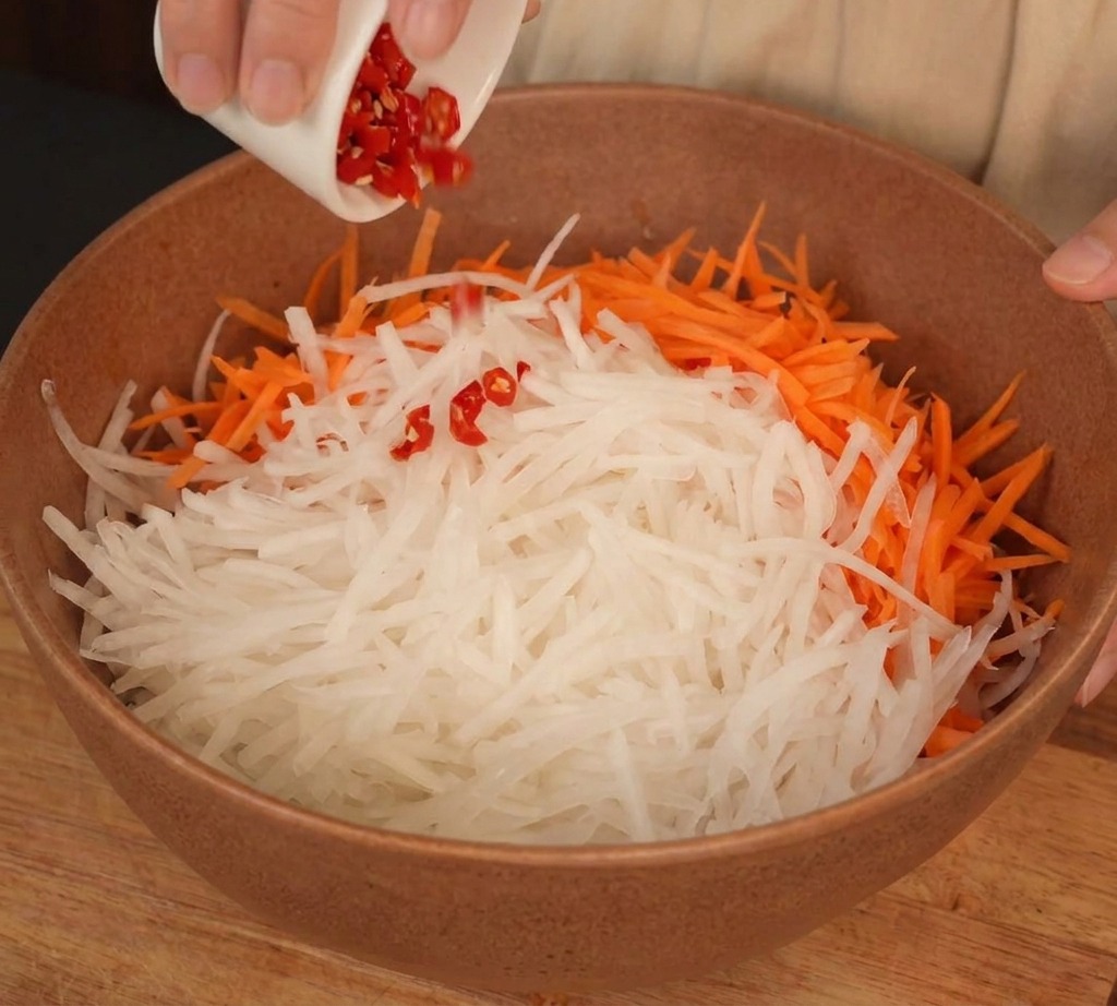 Eine Schüssel mit geraspeltem Rettich, Karotten und fein gehackten Chilischoten.