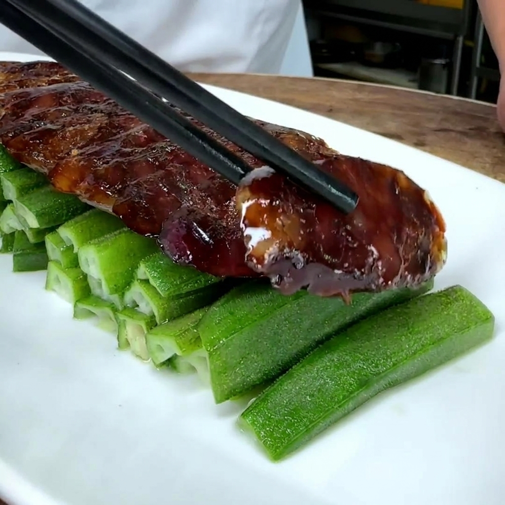 Nahaufnahme von chinesischen Wurstscheiben, die auf einem Bett aus grüner Okra auf einem weißen Teller angerichtet werden.