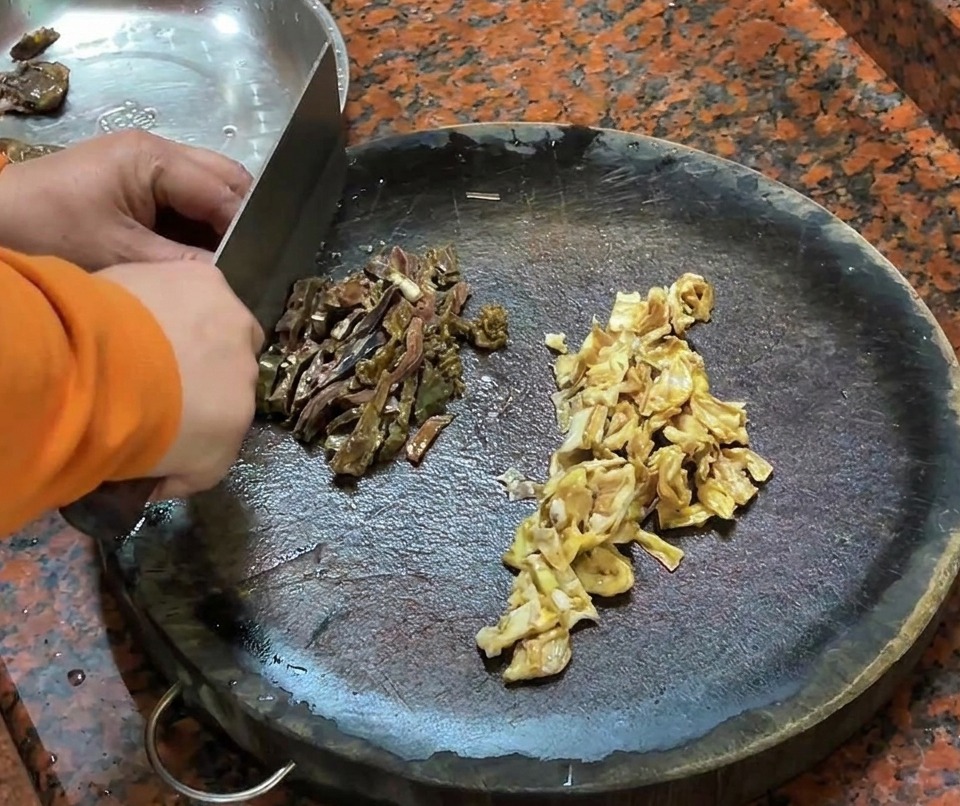 Gehackte Entenleberwurst und Entenhaut auf einem Holzschneidebrett.