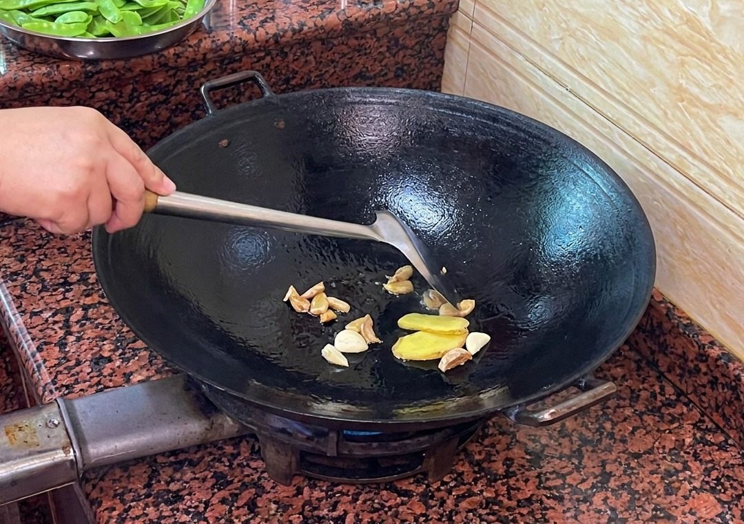 Ingwer- und Knoblauchscheiben braten im Entenfett im Wok.
