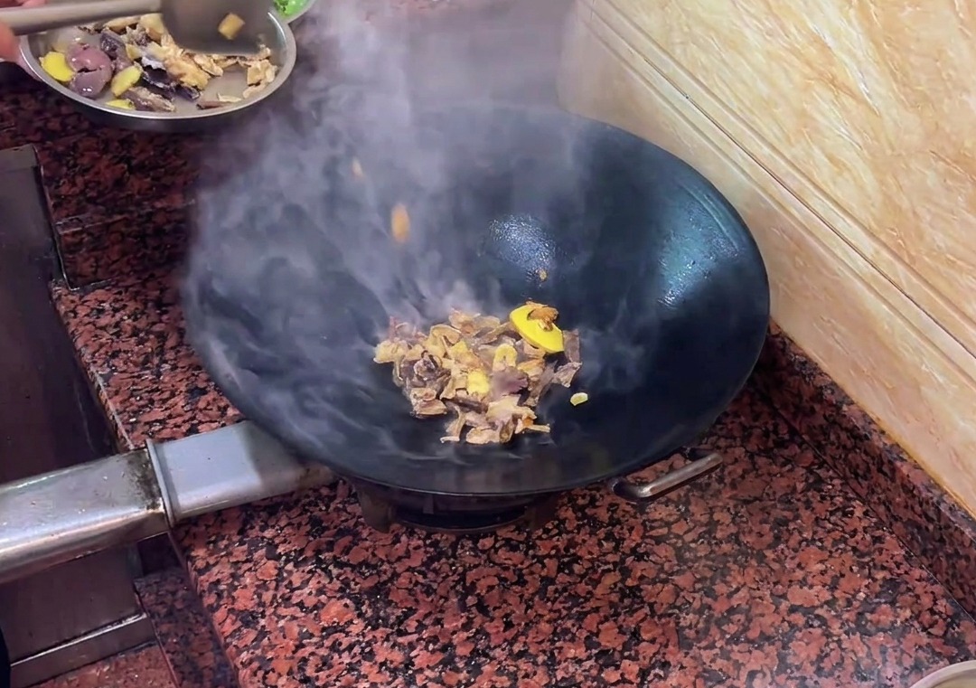 Entenleberwurststücke braten zusammen mit den Aromaten im Wok.