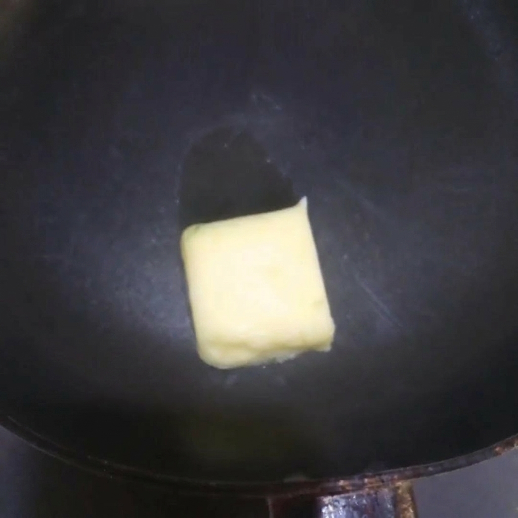 Gelbe Butter schmilzt und zischt in einer heißen Pfanne.