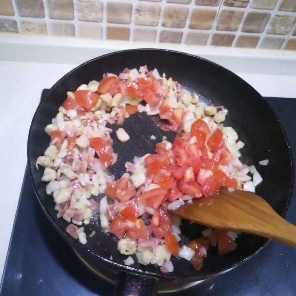 Gewürfelte Tomaten werden zu dem angebratenen Fleisch und den Zwiebeln in die Pfanne gegeben.