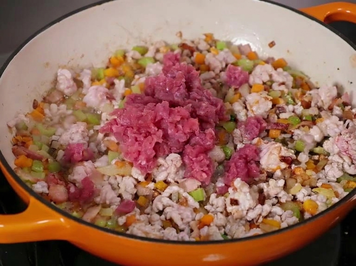 Hackfleisch brät in einer gusseisernen Pfanne mit Gemüse.