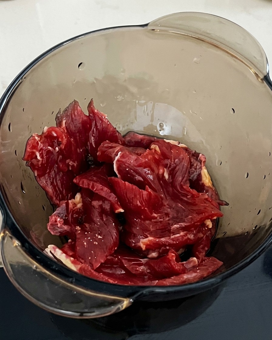 Ein Löffel Stärke wird in die Schüssel mit dem Rindfleisch und der Sojasauce gegeben.