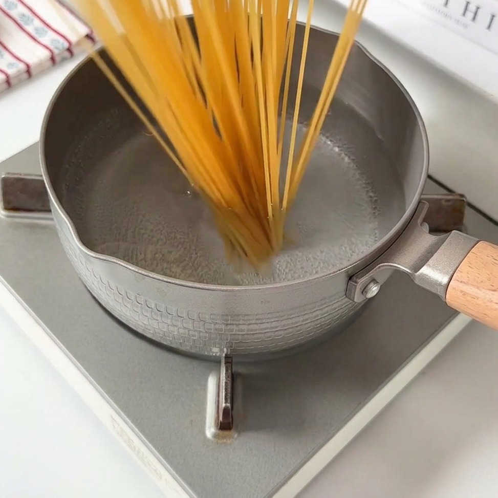 Lange Spaghetti, die in einen Topf mit kochendem Wasser gegeben werden.