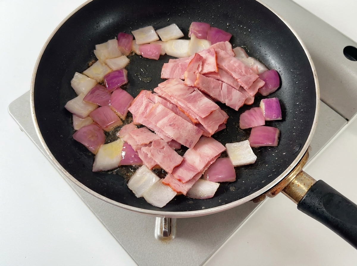 Zwiebeln, Speck und Pilzscheiben werden zusammen in der Pfanne angebraten.