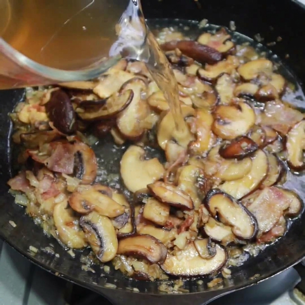 Hühnerbrühe wird in die Pfanne gegossen und köchelt mit der Mischung.