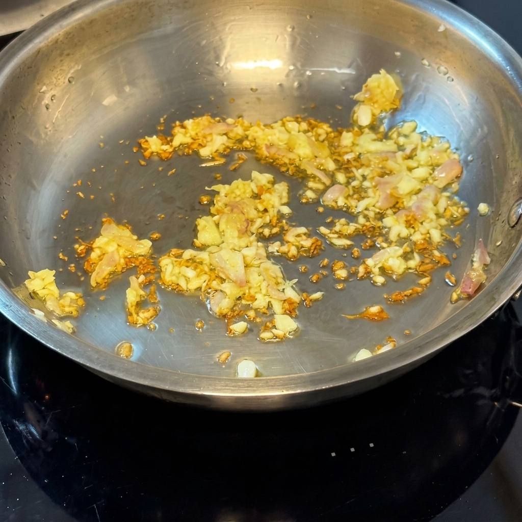 Frische rohe Muscheln werden in die Pfanne zu den gedünsteten Zwiebeln und dem Knoblauch gegeben.