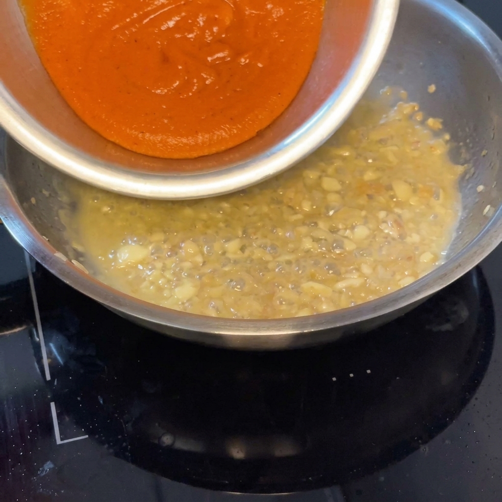 Geröstete Paprikasauce wird in die Pfanne zur Muschelbasis gegeben.