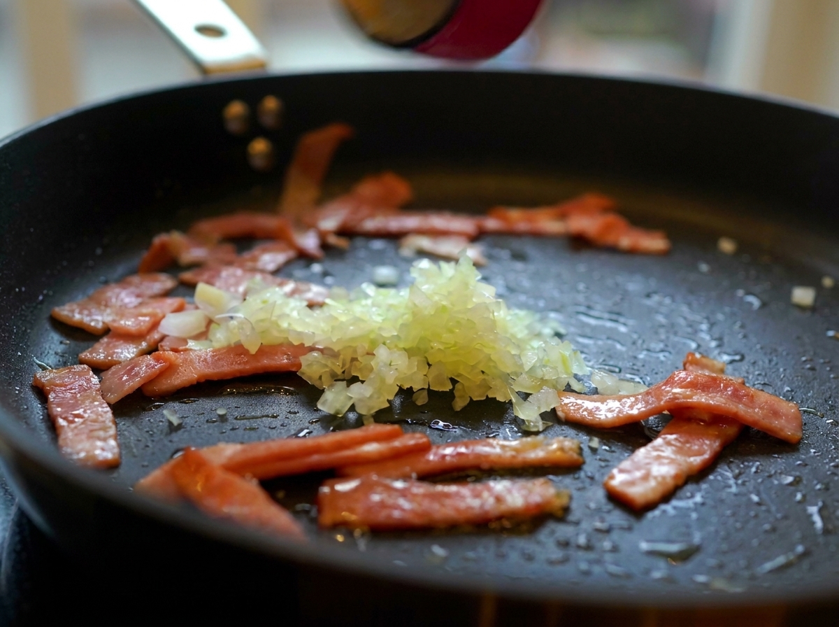 Gehackte Zwiebeln, Knoblauch und Pilzscheiben in einer Pfanne mit knusprigem Speck.