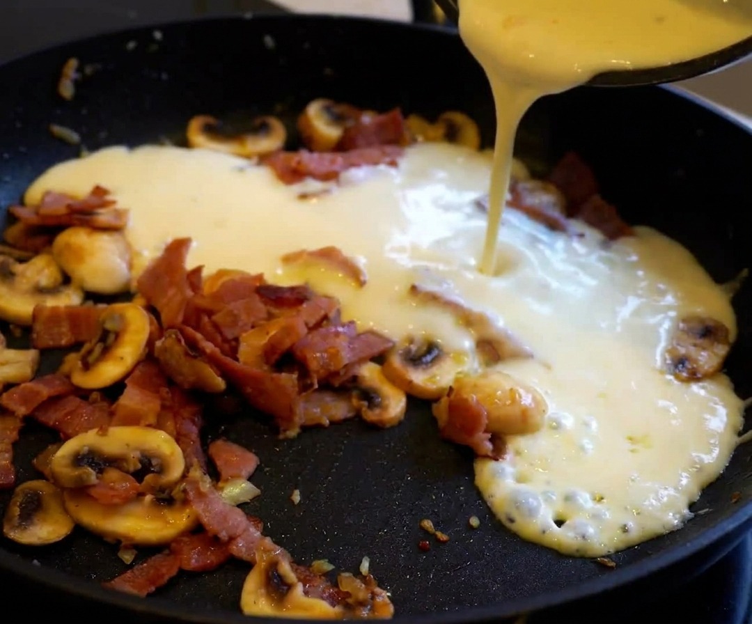 Gekochte Nudeln werden in die Pfanne zur cremigen Sauce gegeben.