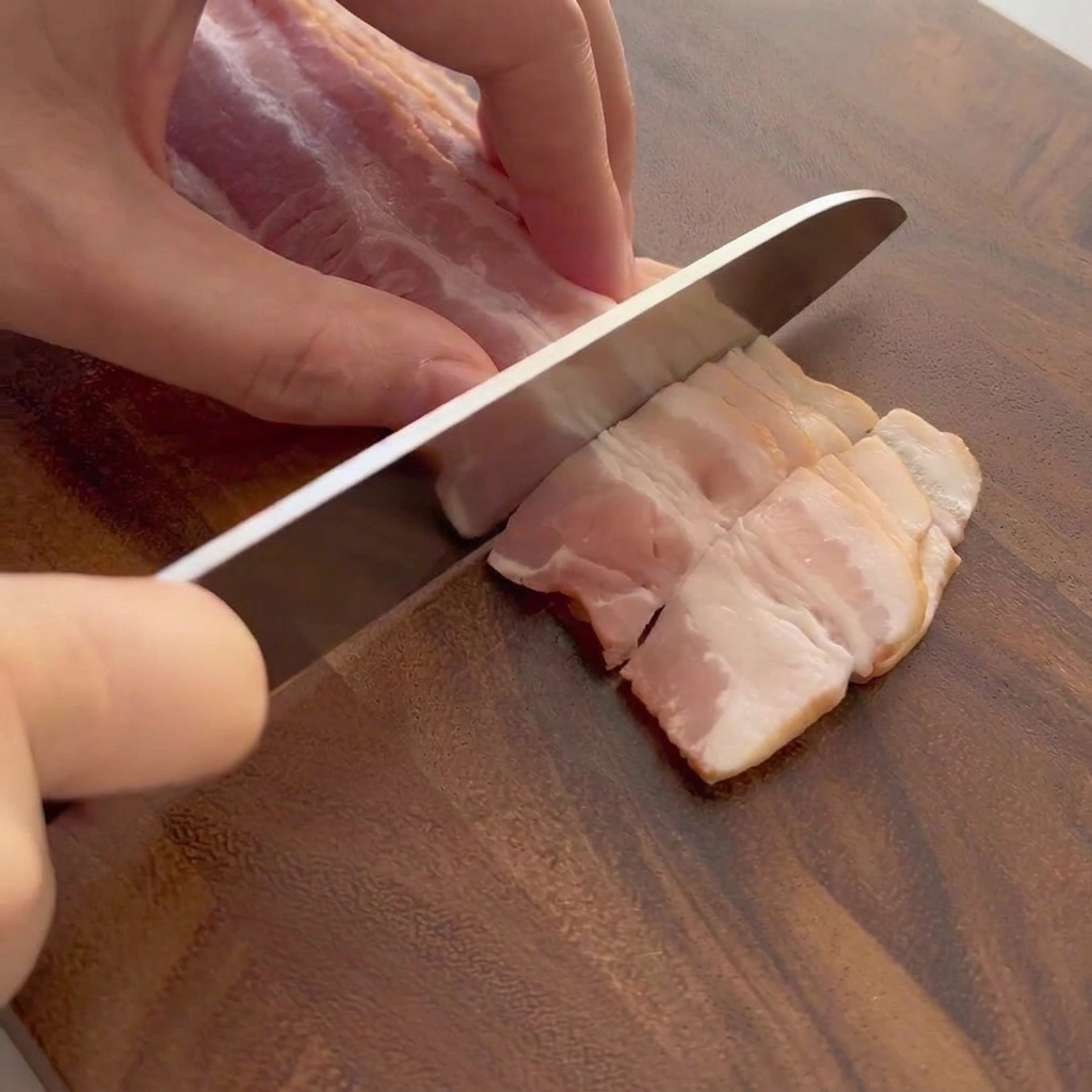 Rohe Speckstreifen, die auf einem Holzschneidebrett geschnitten werden.