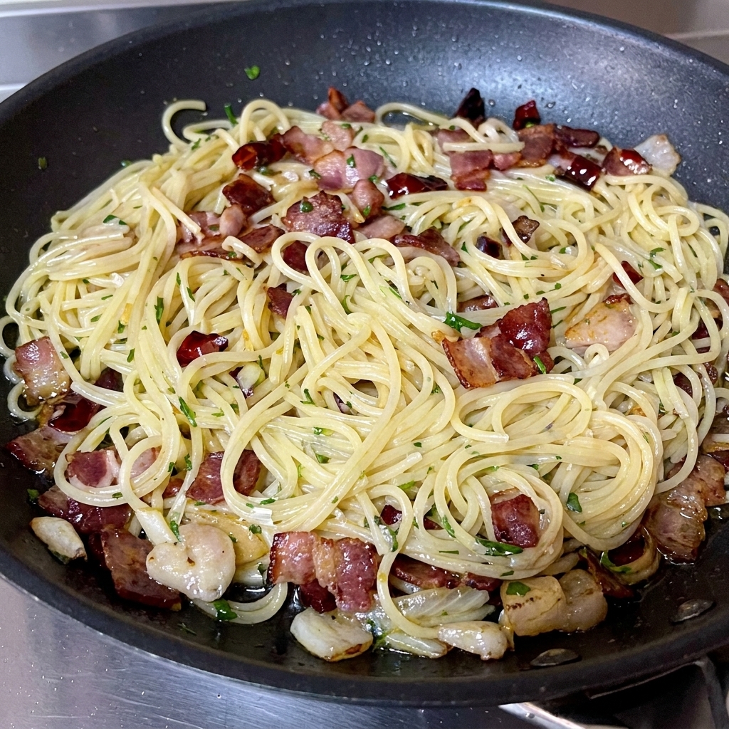 Frisch gehackte grüne Petersilie wird über die fertige Pasta in der Pfanne gestreut.