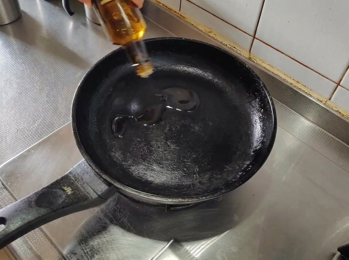 Olivenöl in einer leeren, vorgeheizten schwarzen Pfanne auf dem Herd.