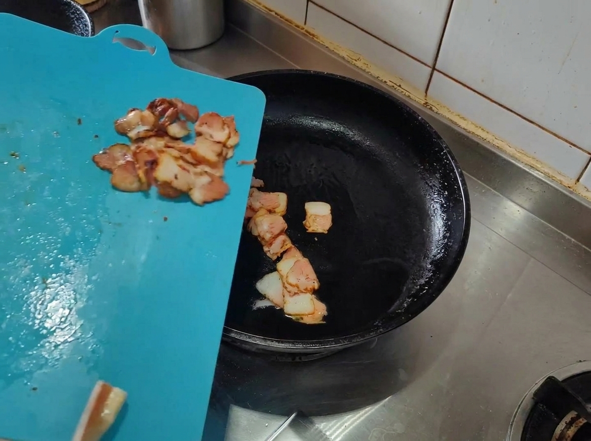 Speckstreifen, die in einer heißen Pfanne mit Olivenöl gebraten werden.