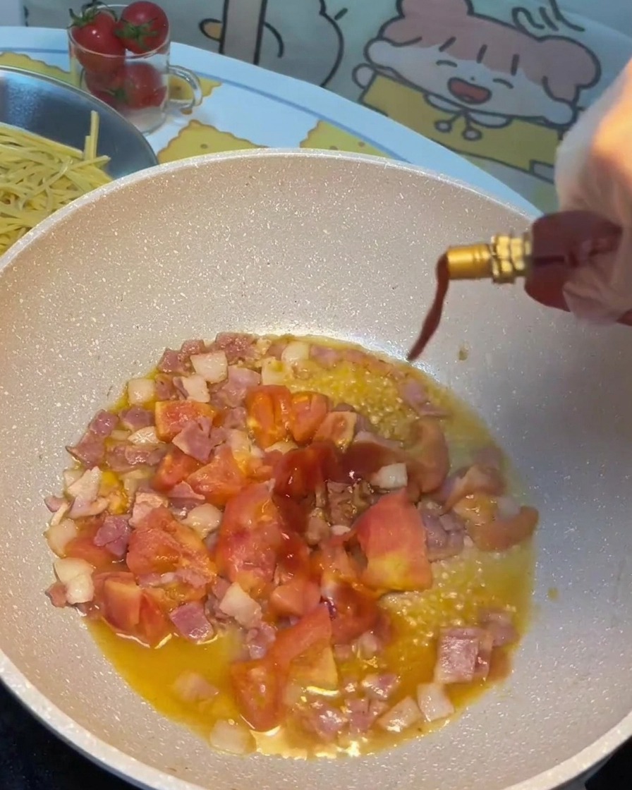 Sojasauce, Tomatensauce und Zucker werden in die Pfanne zu Speck und Tomaten gegossen.