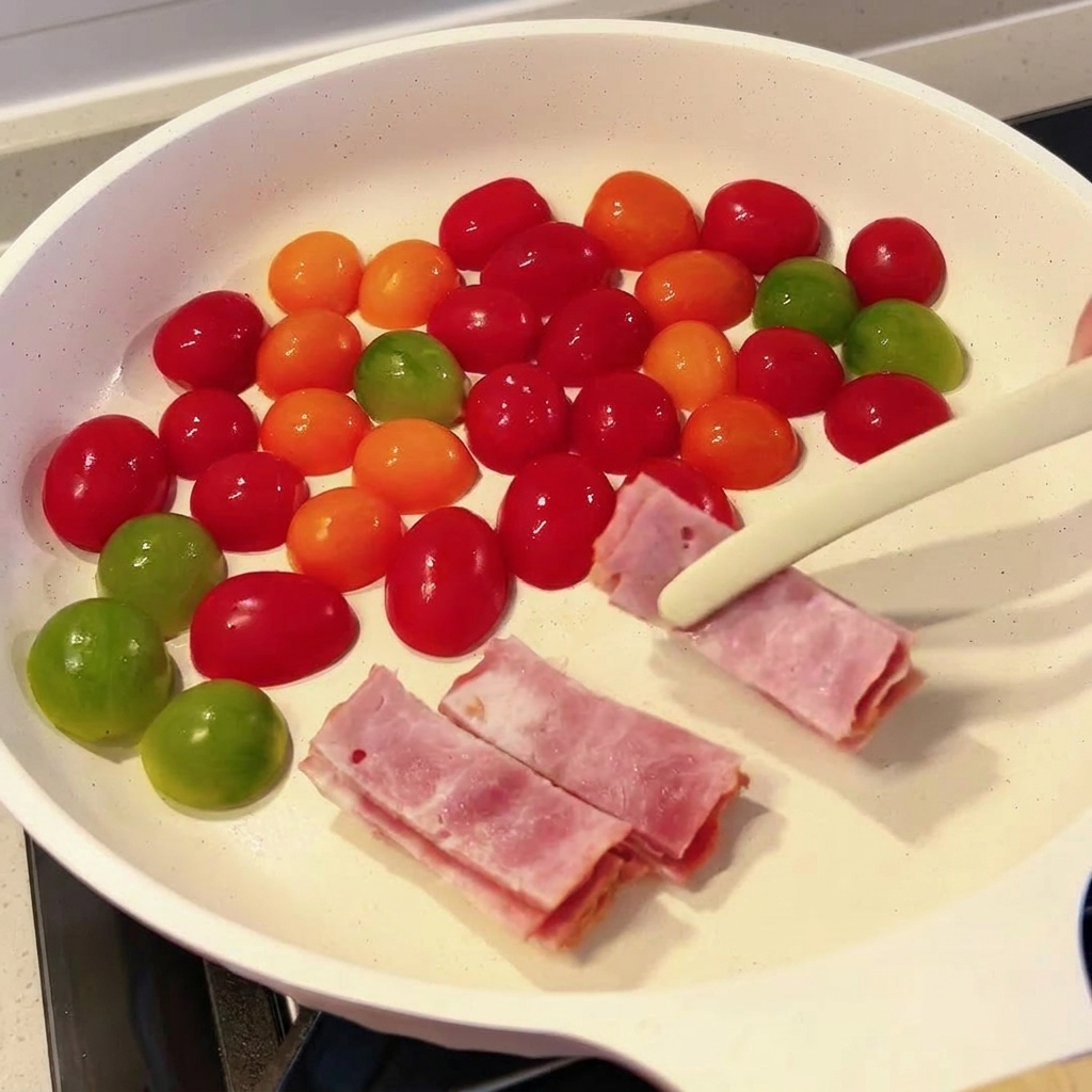 Rohe Speckstreifen werden mit einer Zange in eine Pfanne mit Kirschtomaten gelegt.