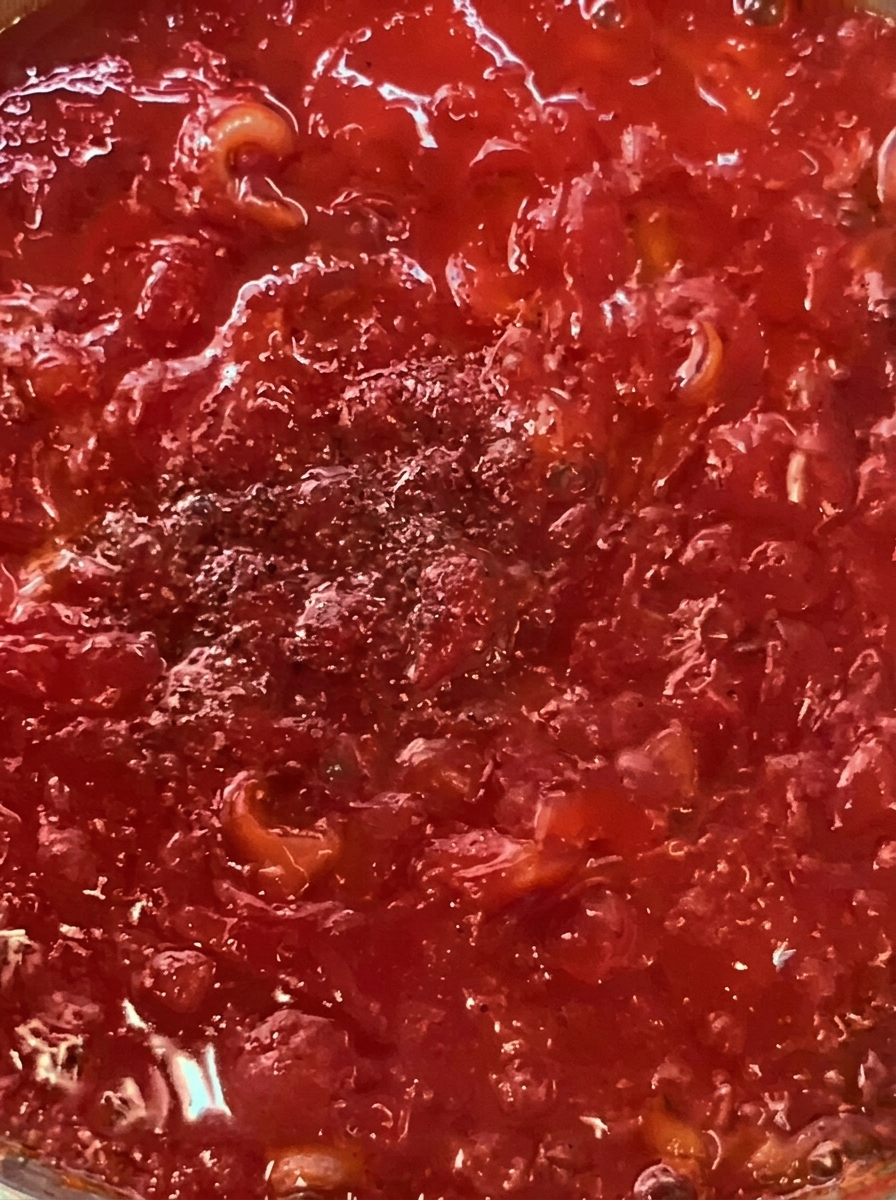 Speckstreifen und Kirschtomaten braten zusammen in einer Pfanne mit Olivenöl.