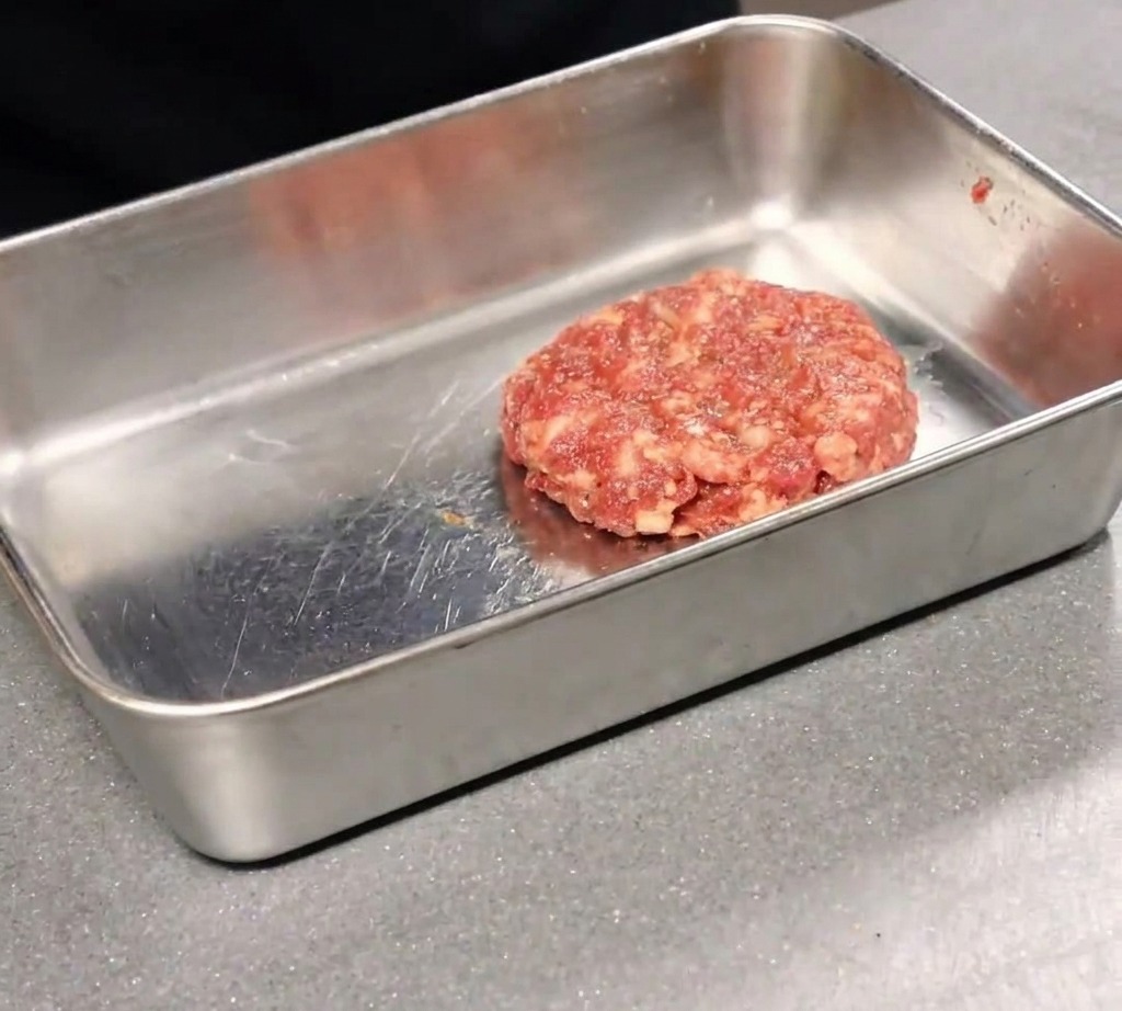 Eine heiße, frisch gebackene Pizza wird mit einem Pizzaschneider zerteilt.