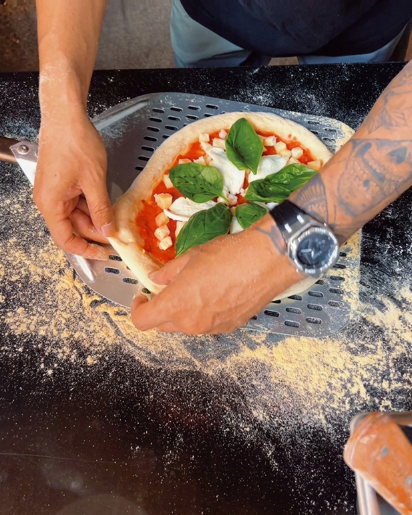 Nahaufnahme frischer Basilikumblätter auf einer belegten Pizza.