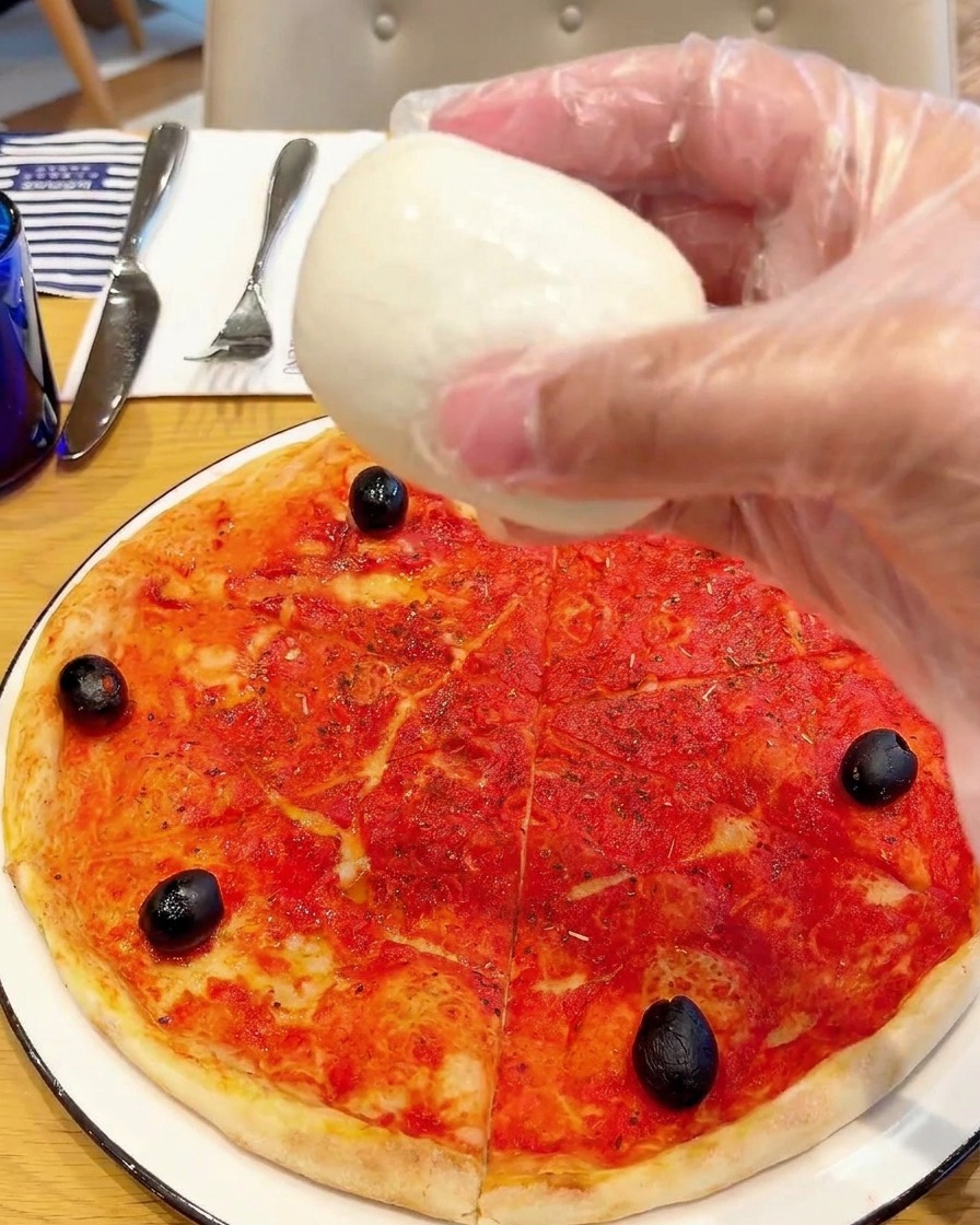 Stücke von frischem Büffelmozzarella werden auf der Pizza platziert.