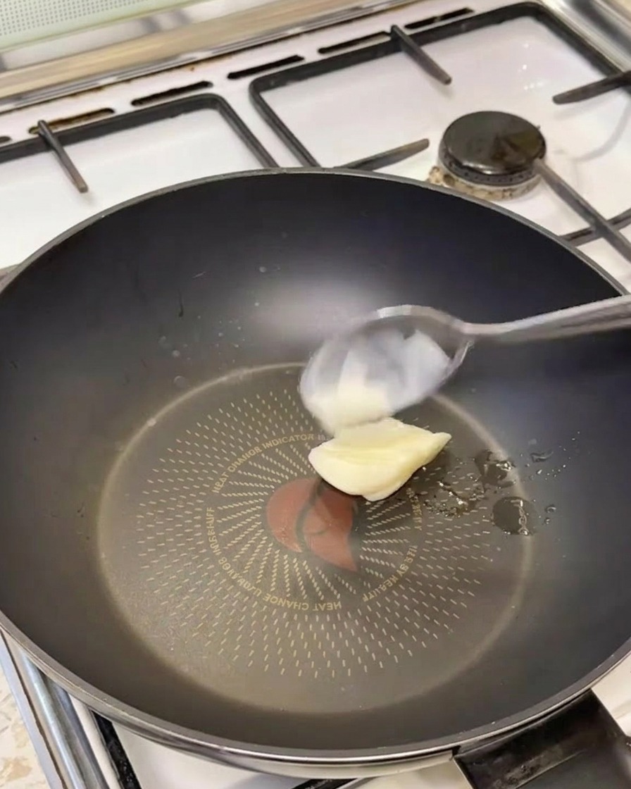 Ein Löffel weißes Schweineschmalz schmilzt in einer heißen Pfanne.
